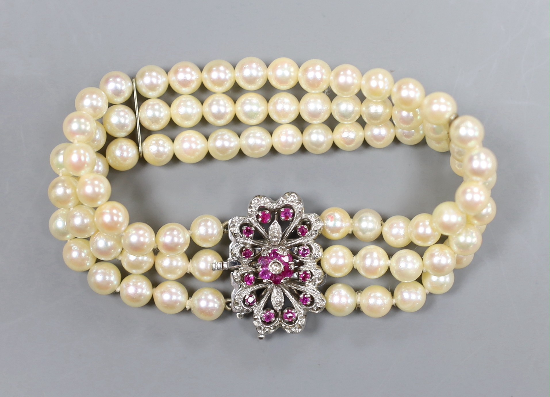 A three strand cultured pearl bracelet with ruby and diamond set 18ct white gold clasp